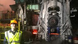EEE student in hi vis jacket and hard hat standing at a steel works