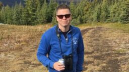 Dr Paul Morris with binoculars and a can of juice out walking.
