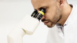 A man observes through a miscroscope.