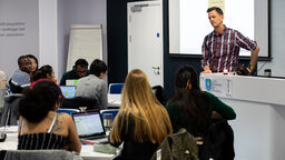 A students asks a question in a lecture and the academic listens intently to the question. 