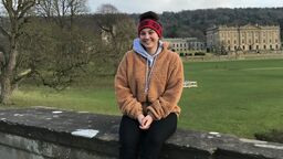 Smiling female Canadian exchange student sits on a wall in the countryside