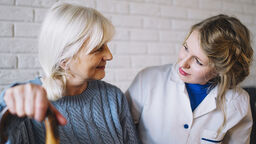 Elderly lady with walking stick and carer