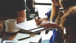 A group of people discussing with a notepad and laptop