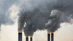 The tops of five chimneys with smoke coming out of them.