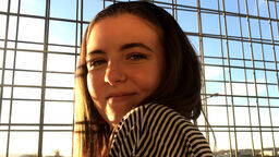 Image of SMI student Ellie, with a city landscape in the background.