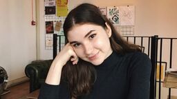 Image of Andreea, politics student ambassador, sat at a desk with a notepad and a cup of tea