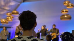 A gig goer stands and watches a live music event.