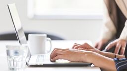 A person's hands typing on a laptop