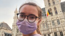 student in Brussels' main square with Belgian flag in the background