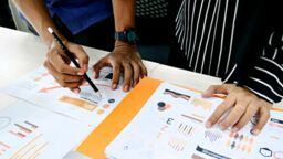 Spreadsheets on the table and two pairs of hands