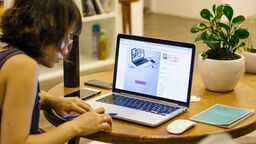Woman working from dining table on laptop