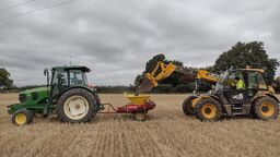 A tractor for spreading receiving crushed basalt from a front-loader at our field site in Harpenden