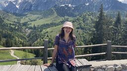 student sitting on a wall with mountains in the background