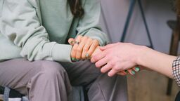 Two people holding hands in comfort.