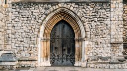 An old looking stone building with an arched heavy wooden door.