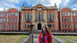 A woman in a red jacket standing in front of a red brick building