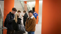 A group of three young people speaking and laughing together.