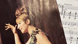 A photo of Barbra Streisand with the score for the song 'Don't Rain on My Parade' in the background