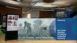 foyer of a building in which you see a poster exhibition and a banner which says slavery ten true stories about Dutch slavery