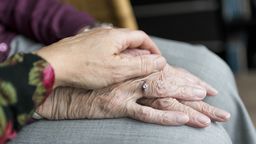 An elderly couple holding hands.