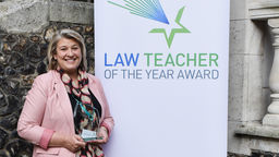 Kate smiling holding the trophy for the Law Teacher of the Year
