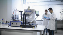 Two researchers looking at a handheld tablet in a lab