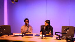 Two women sat at desk with microphones recording a podcast