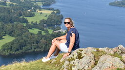 A woman sat on a cliffside in front of a lake