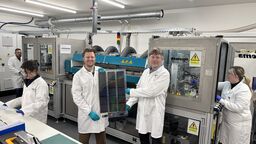 Two researchers in a lab holding solar panel sheet