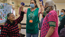 Careworker joining hands with two other people