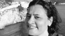 Person smiling with the sea in the background.