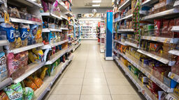 An aisle in a shop showcasing crisps, biscuits and chocolate.