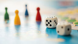 Two dice and four playing pieces on a board game board