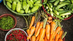 Bowls of fresh food including carrots, cucumbers and chillies
