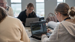 Students sit around laptops