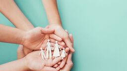 Hands cupping a paper chain of cut out people