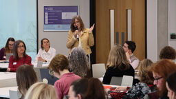 Professor Katherine Runswick-Cole holding a microphone addressing a group of people
