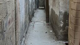 A narrow alleyway with window shutters opening onto it