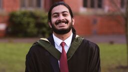 Alumni Adithya Ajith wearing graduation gown outside Firth Court