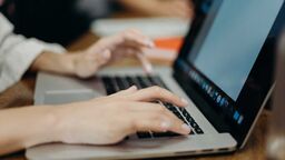 Hands typing on a laptop