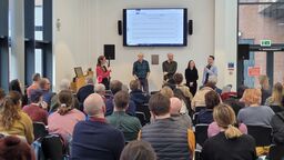 An audience listening to a panel of four speakers at the Reflections on COP event