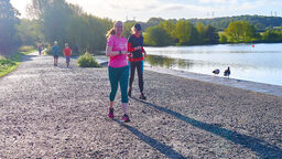 Runner on path by lake in sunny weather