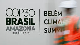A worker puts up a banner at the "Convention and Exhibition Centre" in Belém for COP30.