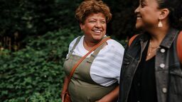 Two women walking and smiling at one another