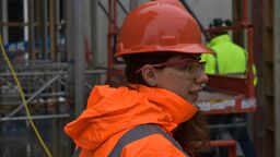 woman with red hard hat and orange reflective jacket