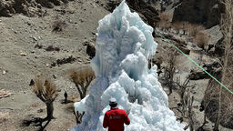 A man standing in front of an artificial ice reservoir in the Indian Himalayas
