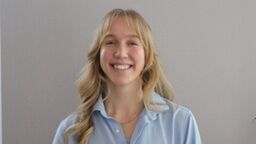 Student Holly Phillips stood in front of a grey background