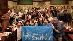 A group of Sheffield alumni in Japan posing for a picture with a University flag