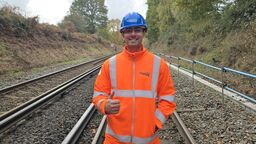 An general engineering alumnus is standing on the rail with his Network Rail uniform