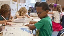 Children using work books in a classroom
